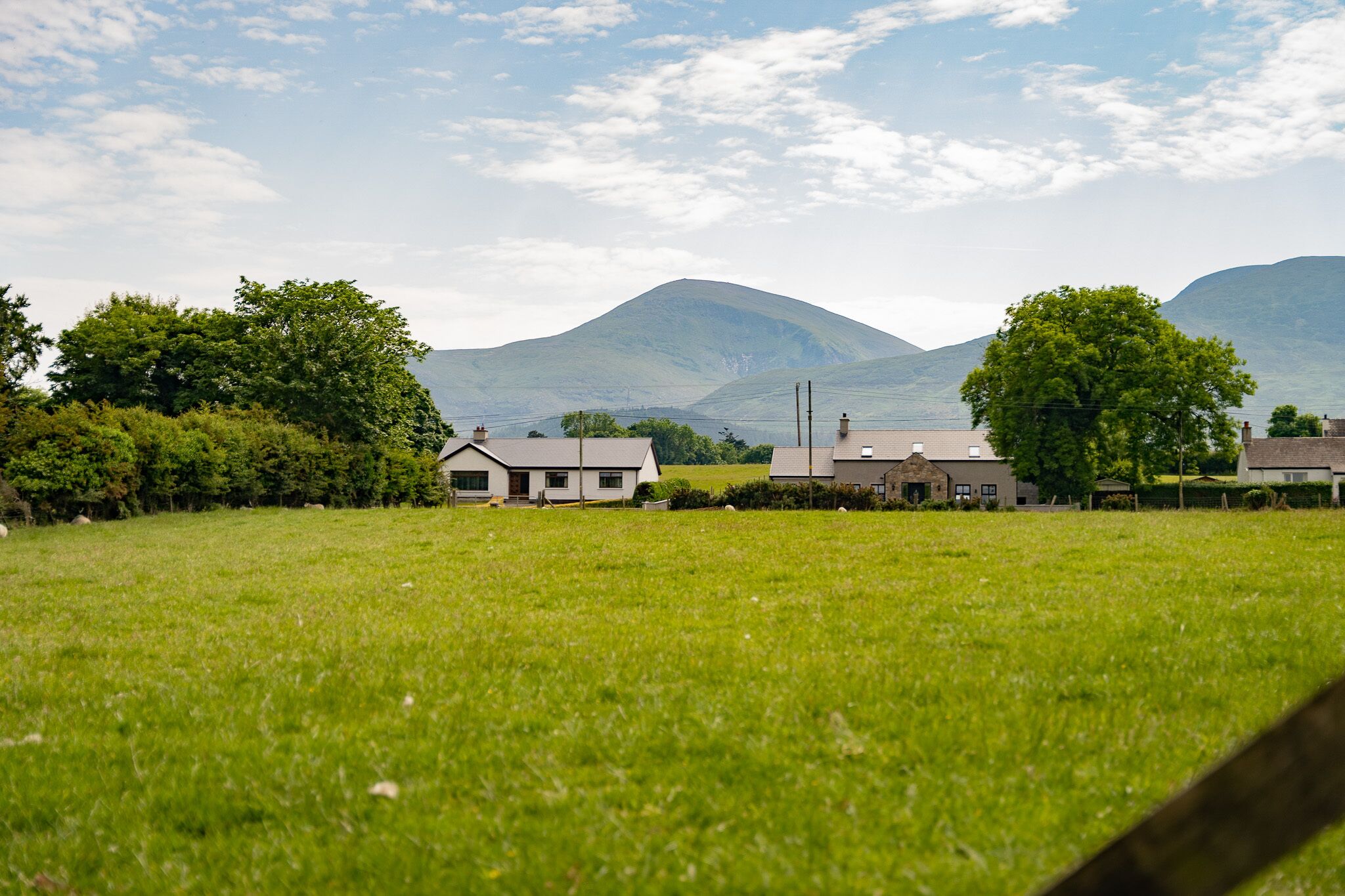 Paesaggio rurale con case e una montagna sullo sfondo.