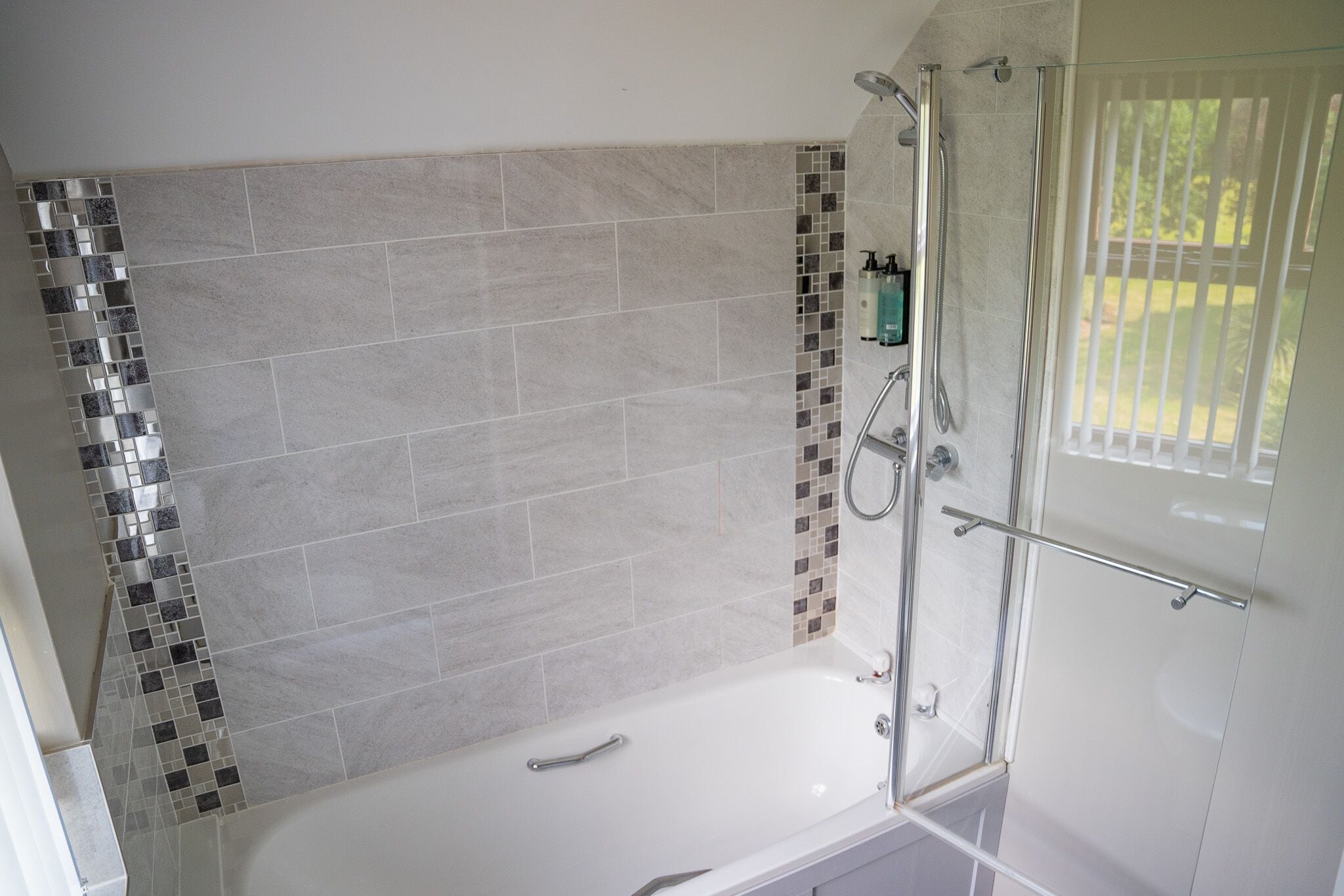 Un baño moderno con cabina de ducha de vidrio, una bañera y zona de ducha revestida con azulejos.