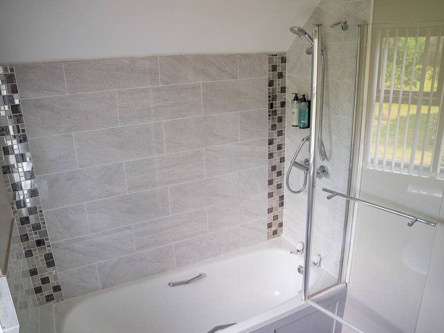Un baño moderno con cabina de ducha de vidrio, una bañera y zona de ducha revestida con azulejos.