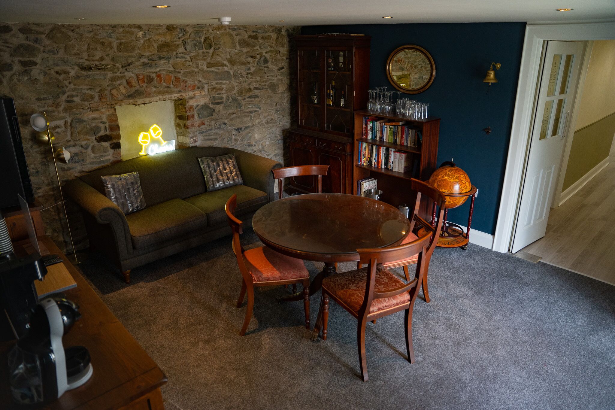 A cozy living room with a stone wall, a wooden dining table, and a bookshelf.