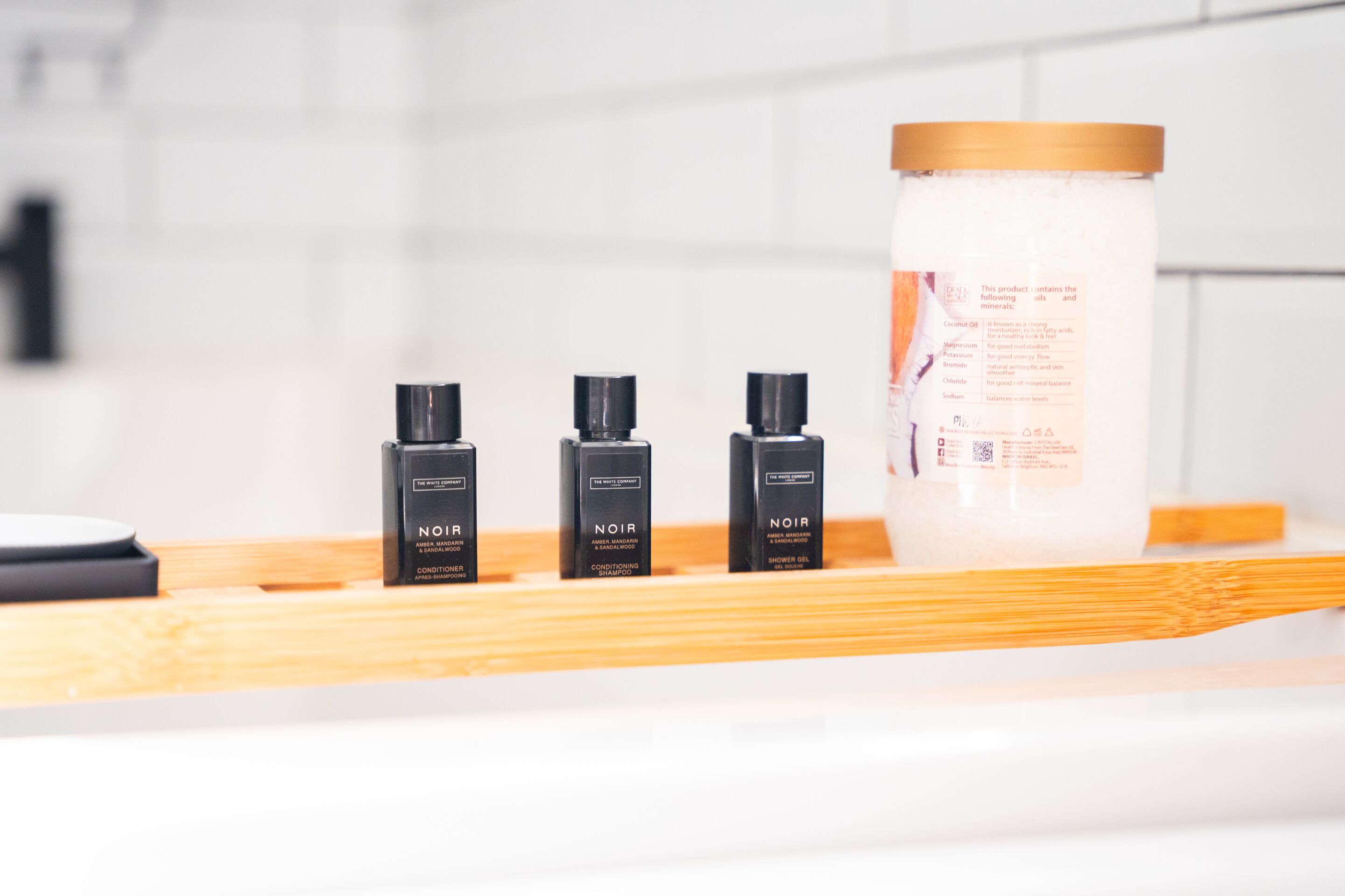 Een badkamerplankje met drie flessen Noir conditioner en een grote verpakking body lotion.