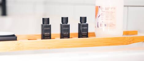 Een badkamerplankje met drie flessen Noir conditioner en een grote verpakking body lotion.
