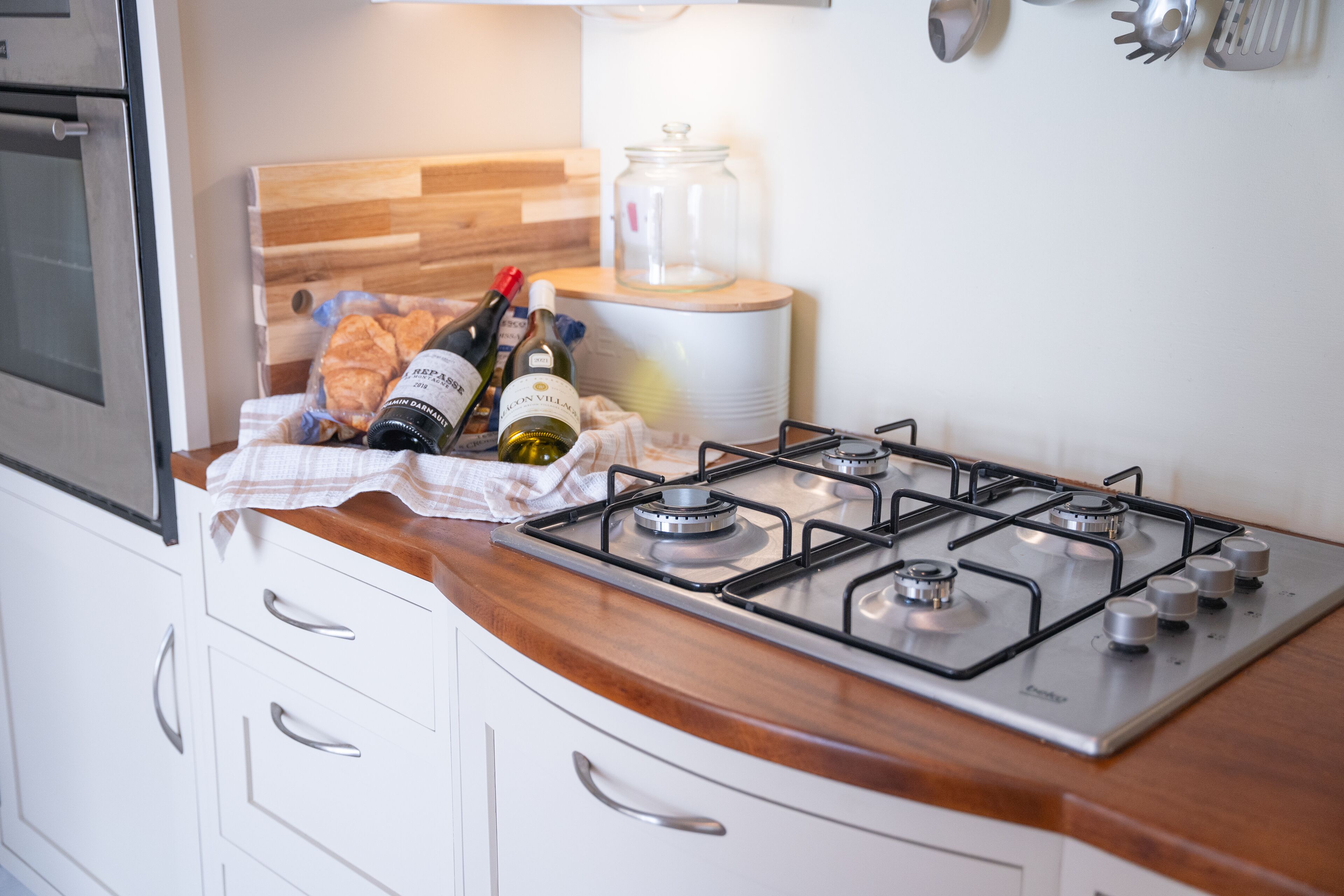 Une cuisine équipée d’une cuisinière à gaz, de meubles blancs et d’un plan de travail en bois.