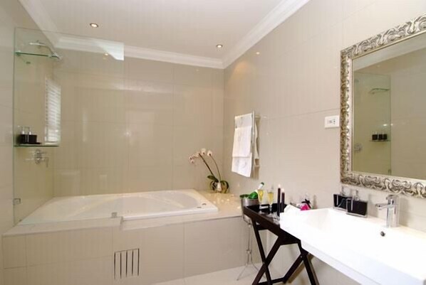 A modern bathroom with a large bathtub, a vanity with a mirror, and a glass shower enclosure.