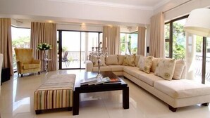 A spacious living room with a large sofa, a coffee table, and a chair. - Sanchia Luxury Guesthouse (Durban North)