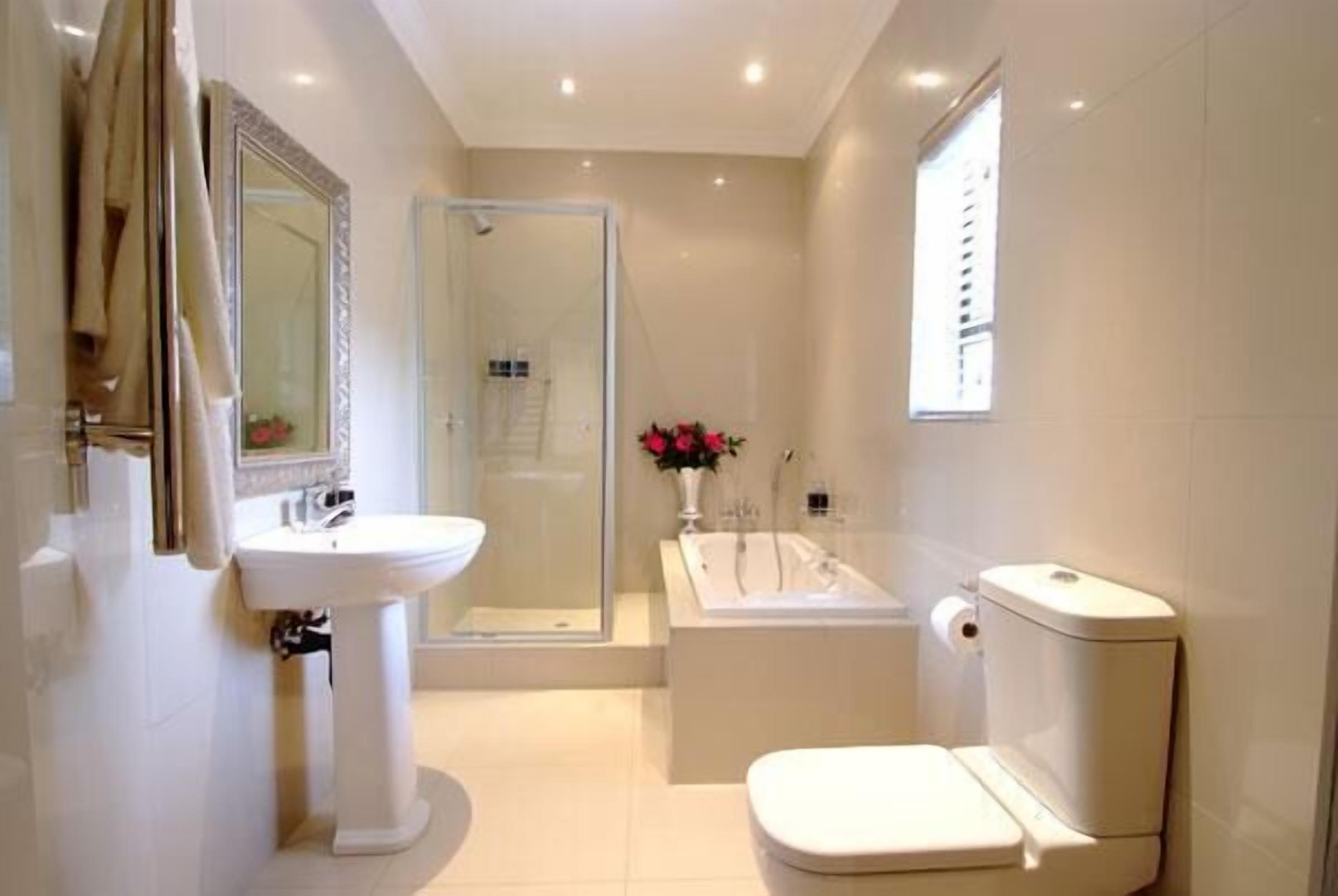A modern bathroom with a pedestal sink, a bathtub, and a toilet.