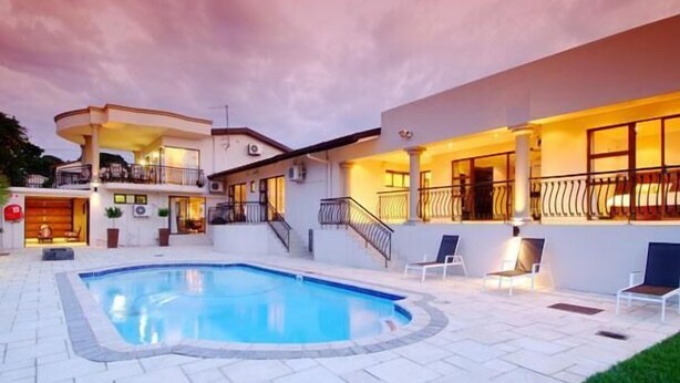 A modern house with a swimming pool, outdoor seating, and a well-lit balcony. - Sanchia Luxury Guesthouse (Durban North)