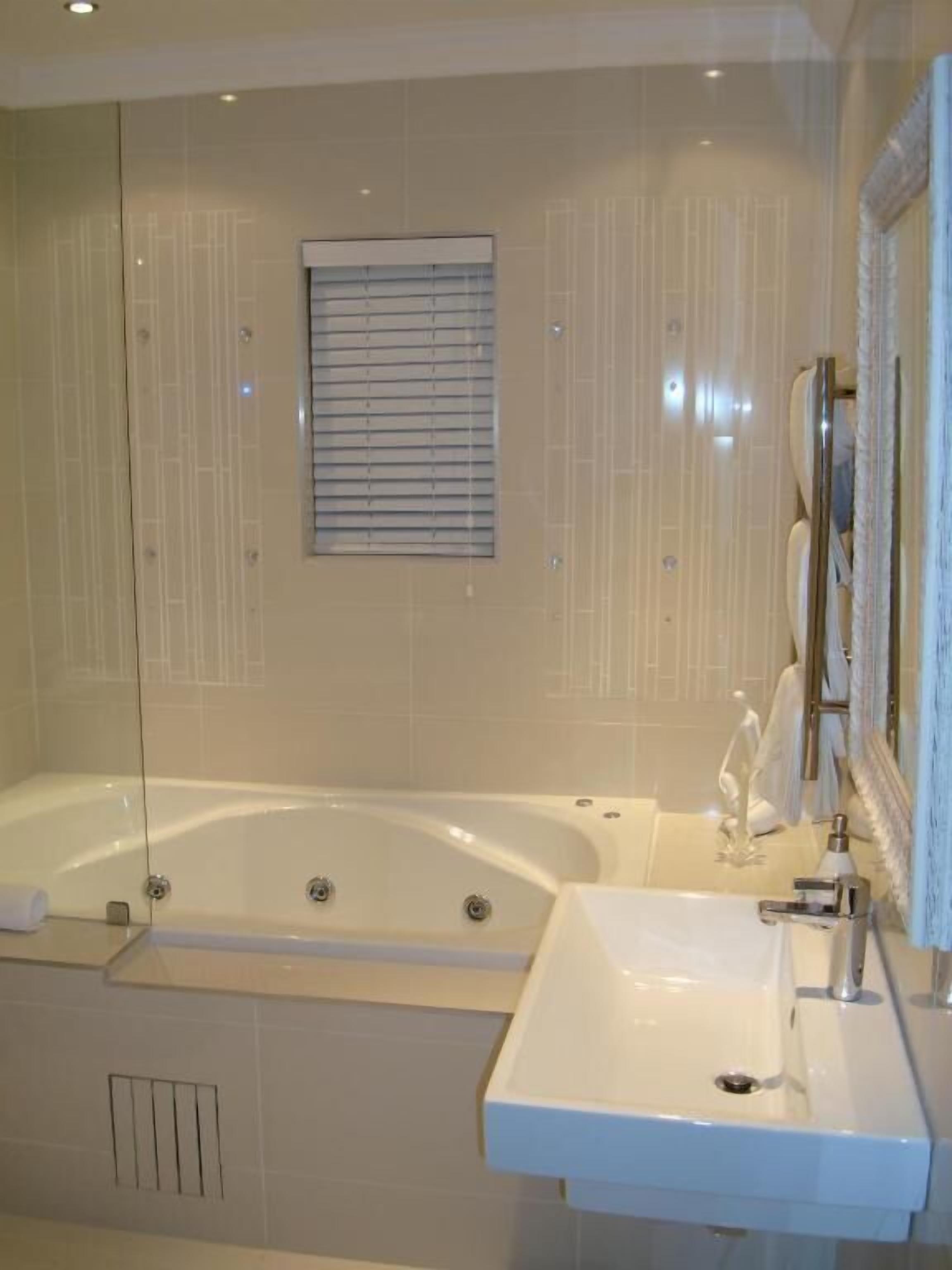Un baño moderno con una bañera independiente, un lavabo y un espejo.