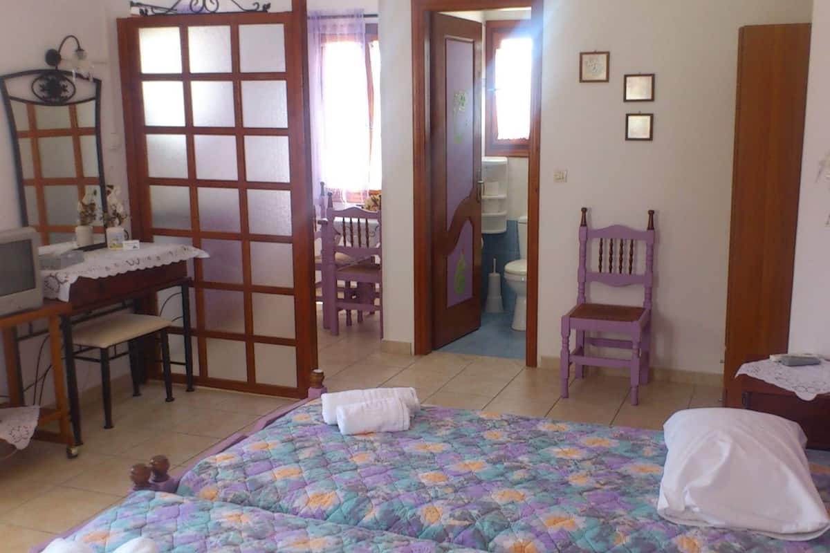 A bedroom with a bed, a desk, a chair, and a wardrobe.
