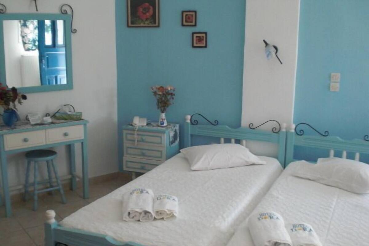 A bedroom with a bed, two bedside tables, a dresser, a mirror, and a wall with a picture.