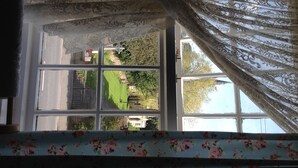 A window with floral curtains and a view of a garden and a building outside. - Church View B&B and Holiday Cottages (York)