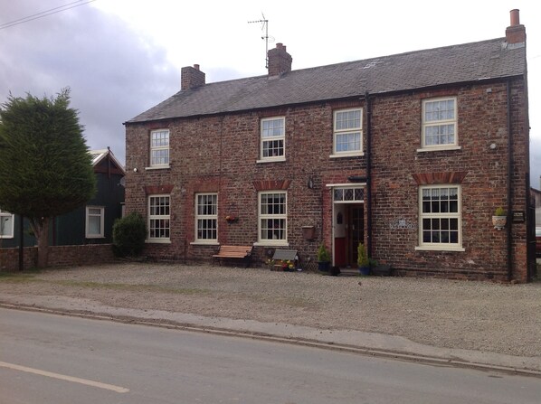 A two-story brick building with a traditional design, featuring multiple windows and a welcoming entrance. - Church View B&B and Holiday Cottages (York)