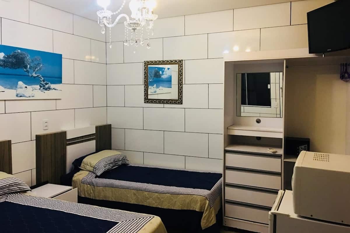 Camera d'albergo con due letti, una cassettiera, uno specchio, una televisione e un lampadario.