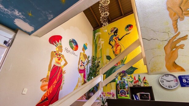 A staircase with colorful murals, a clock, and a chandelier. - Hotel das Palmas (Florianópolis)