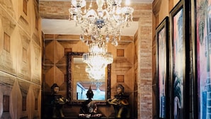 A hallway with a chandelier, a mirror, and Buddha statues. - Hotel das Palmas (Florianópolis)