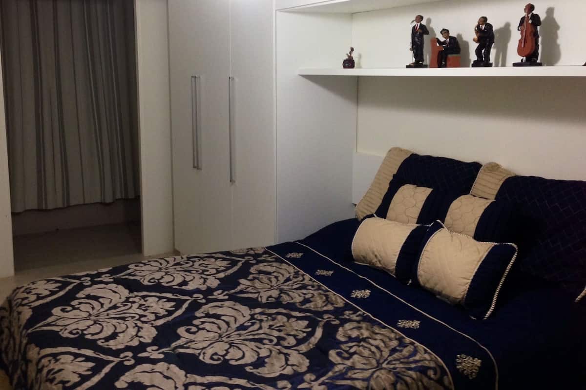 Una camera da letto con un letto, un armadio, uno scaffale con figurine e una tenda.
