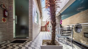 A corridor with a tiled floor, a potted palm tree, a fire extinguisher, and a door marked with the number 8. - Hotel das Palmas (Florianópolis)