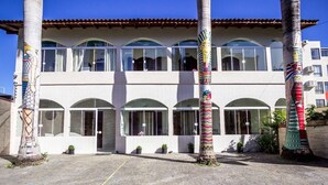 A building with a white facade, multiple balconies, and decorative pillars. - Hotel das Palmas (Florianópolis)