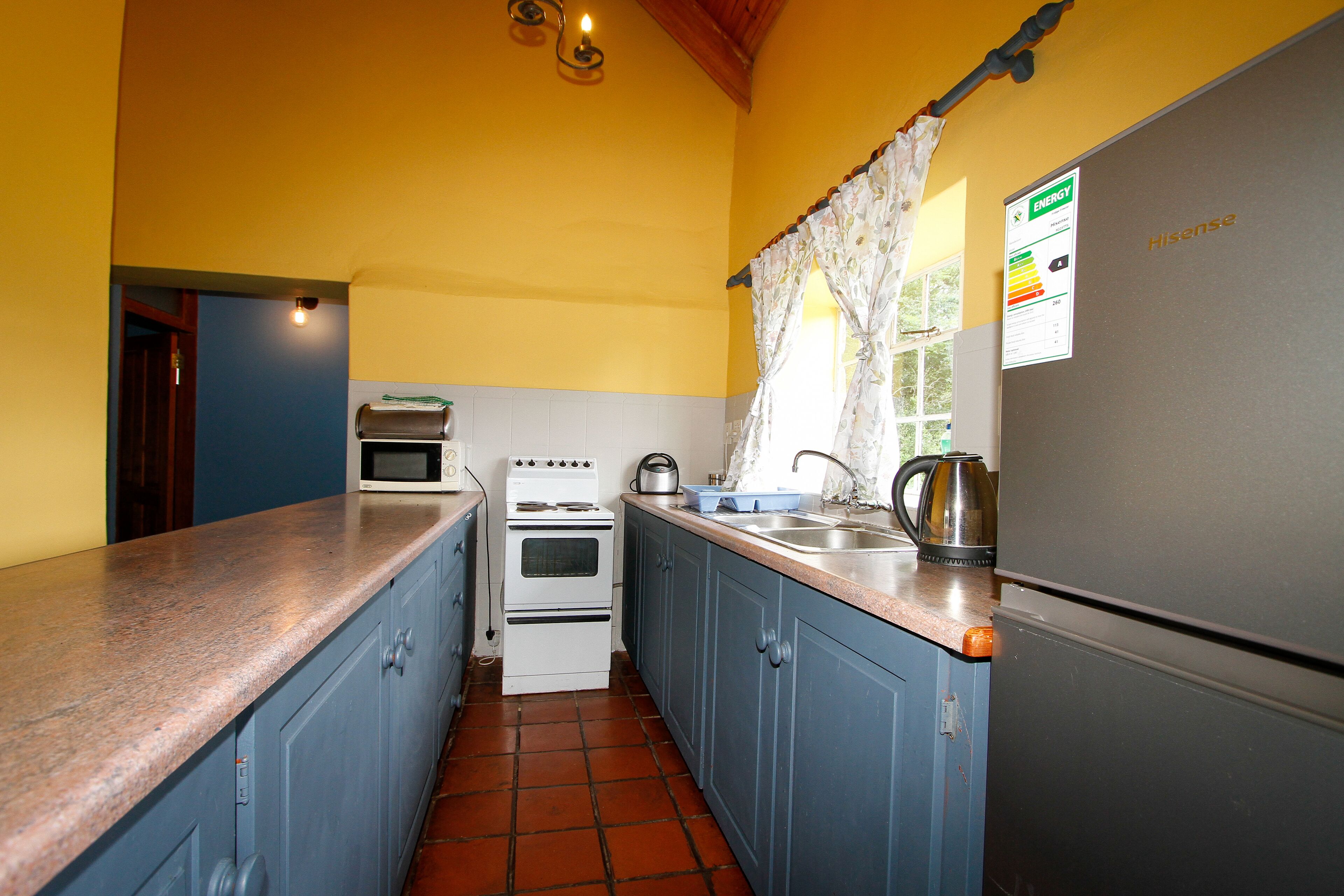 A compact kitchen with blue cabinets, a white stove, and a stainless steel refrigerator.