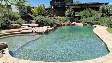 Una piscina al aire libre, sombrillas, sillones reclinables de piscina