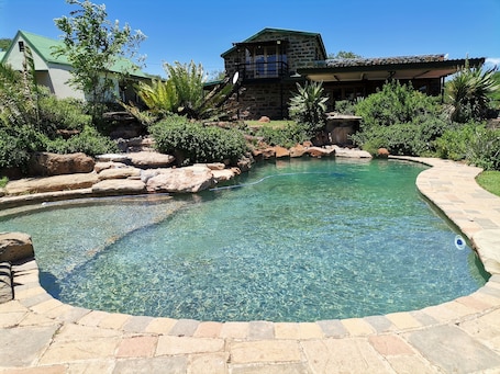 Una piscina al aire libre, sombrillas, sillones reclinables de piscina