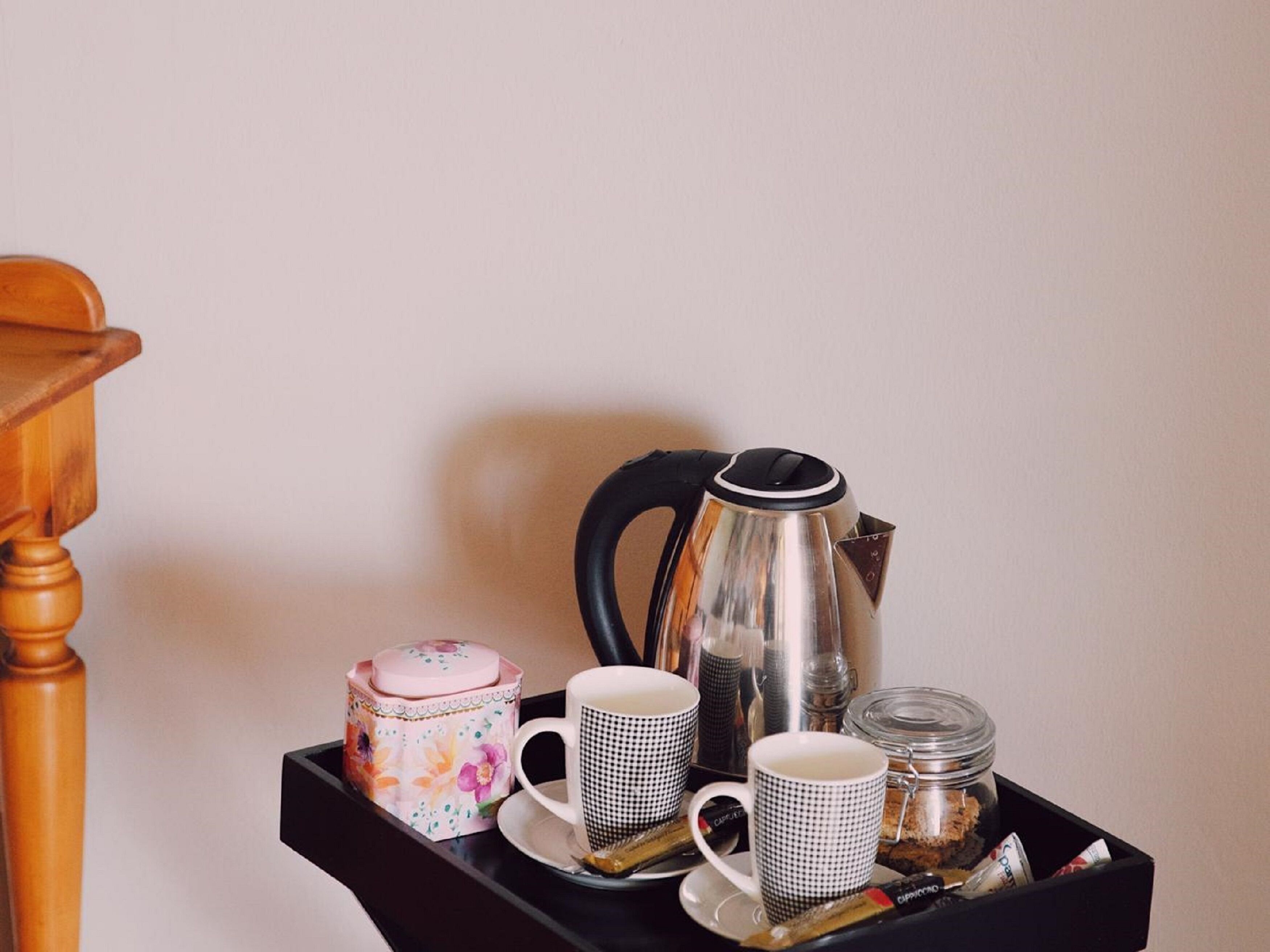 A tray with a coffee maker, two cups, a sugar container, and a creamer jar.