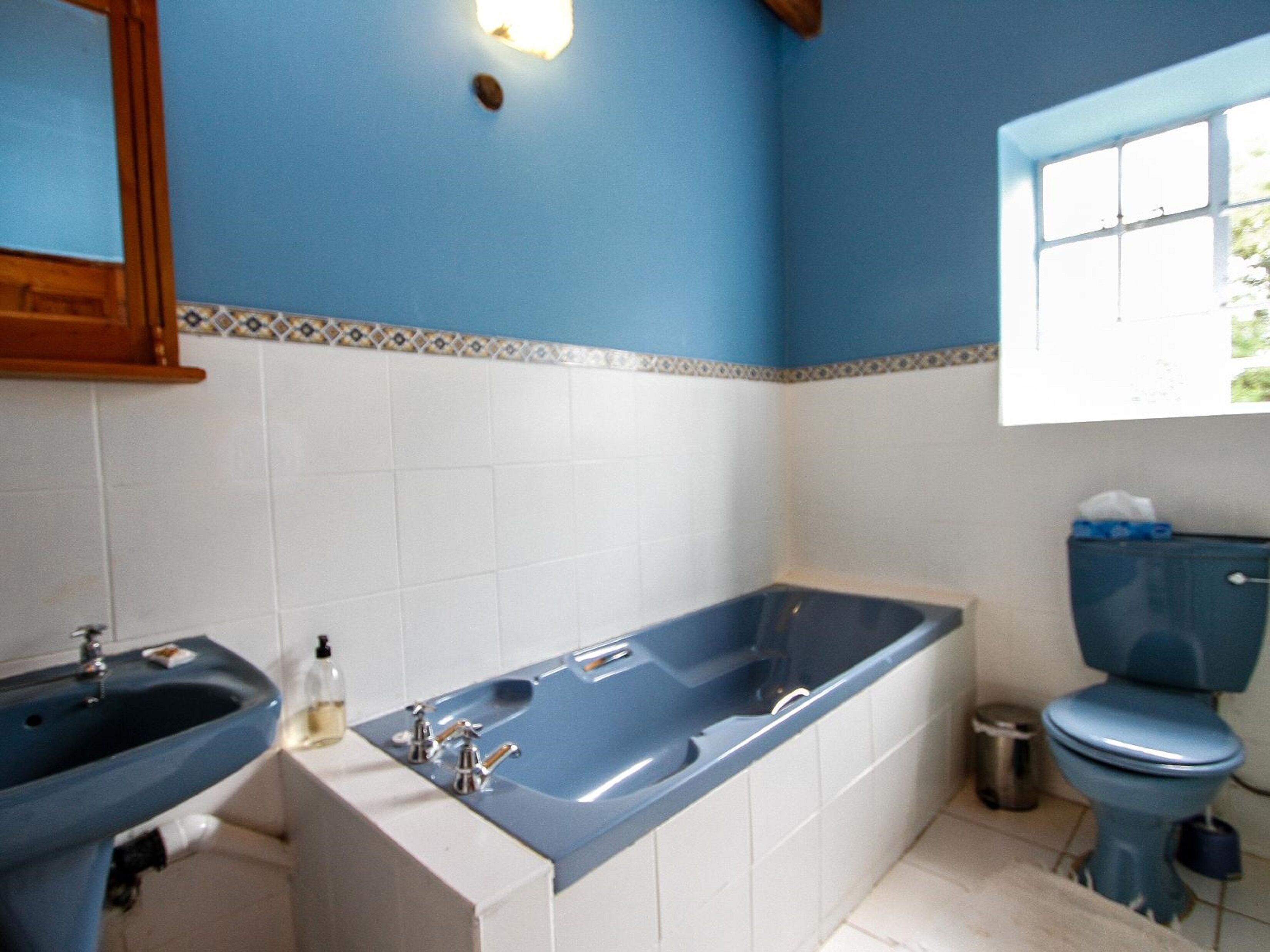 A bathroom with a blue bathtub, a sink, and a toilet.
