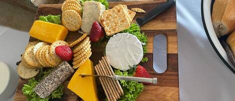 A charcuterie board with various cheeses, crackers, and strawberries.