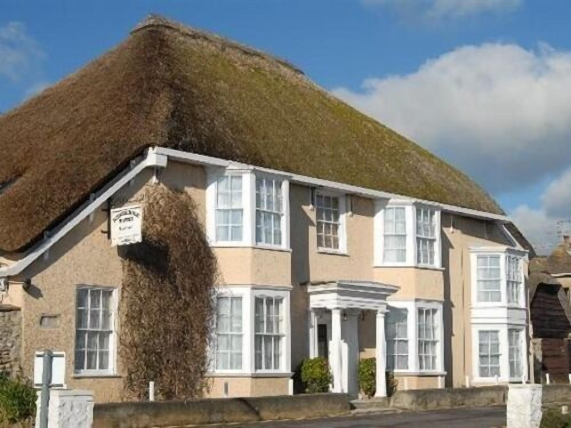 A traditional building with a thatched roof, multiple windows, and a sign indicating it is a pub.