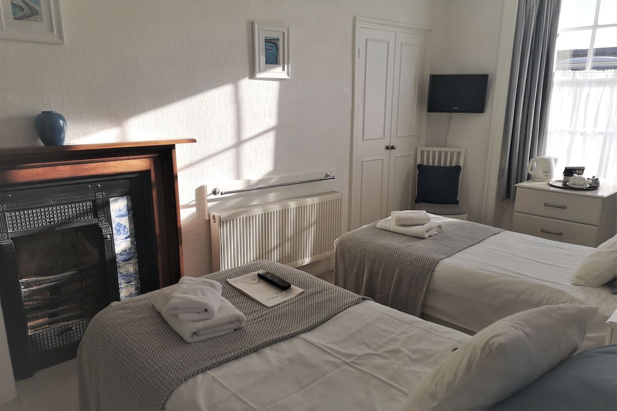 Habitación de hotel con dos camas, chimenea, televisor y ventana con cortinas.