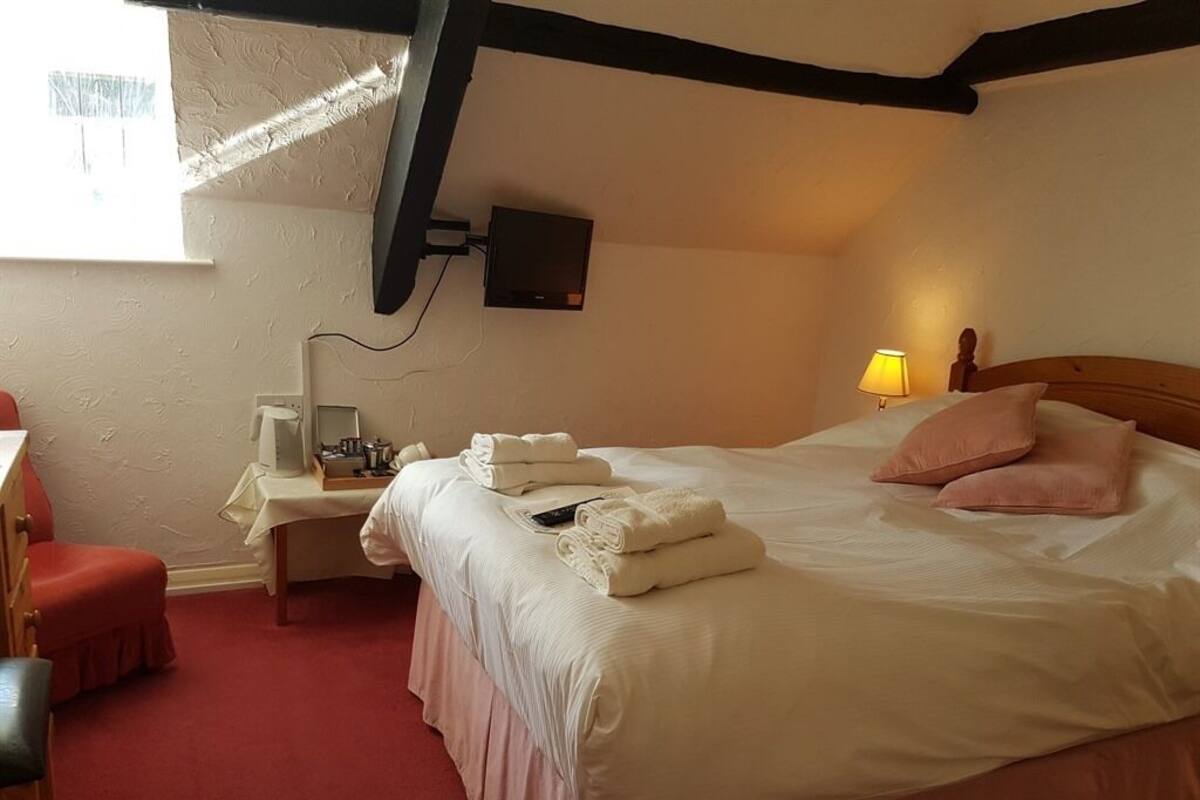 Una habitación de hotel con una cama, un escritorio con lámpara, un televisor y una silla.
