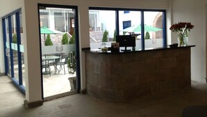 A reception area with a stone counter, a glass door leading to an outdoor patio with umbrellas and chairs. - Tierra Viva Cusco Centro (Cusco)
