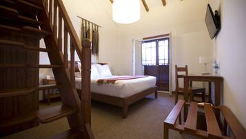 A bedroom with a wooden bed, a desk, and a chair.