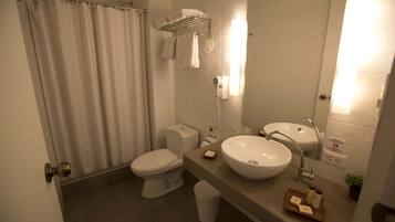 Une salle de bain moderne équipée de toilettes, d’un bidet, d’un lavabo et d’un rideau de douche.