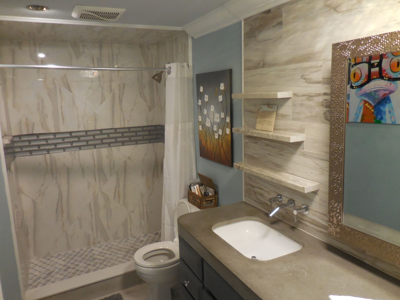 A bathroom with a shower, toilet, sink, and a decorative mirror.