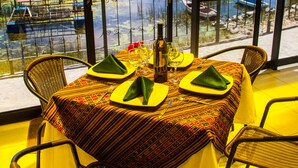 A dining area with a table set for four, overlooking a body of water with boats and a dock. - Yacht Lago Titicaca (Puno)