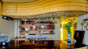 A bar area with a wooden ceiling, wine glasses hanging above, and a variety of bottles and decorations on shelves. - Yacht Lago Titicaca (Puno)