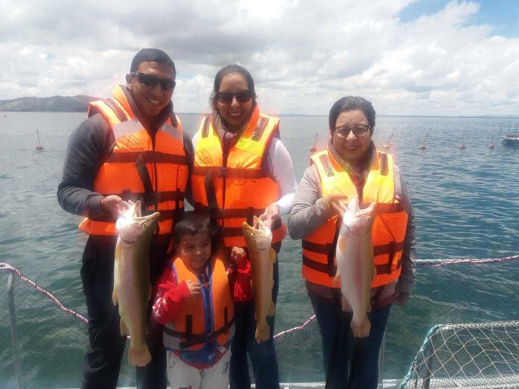 A group of people on a boat, wearing life jackets, holding fish.