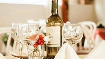 Una mesa dispuesta con copas de vino, una botella y un jarrón con flores.