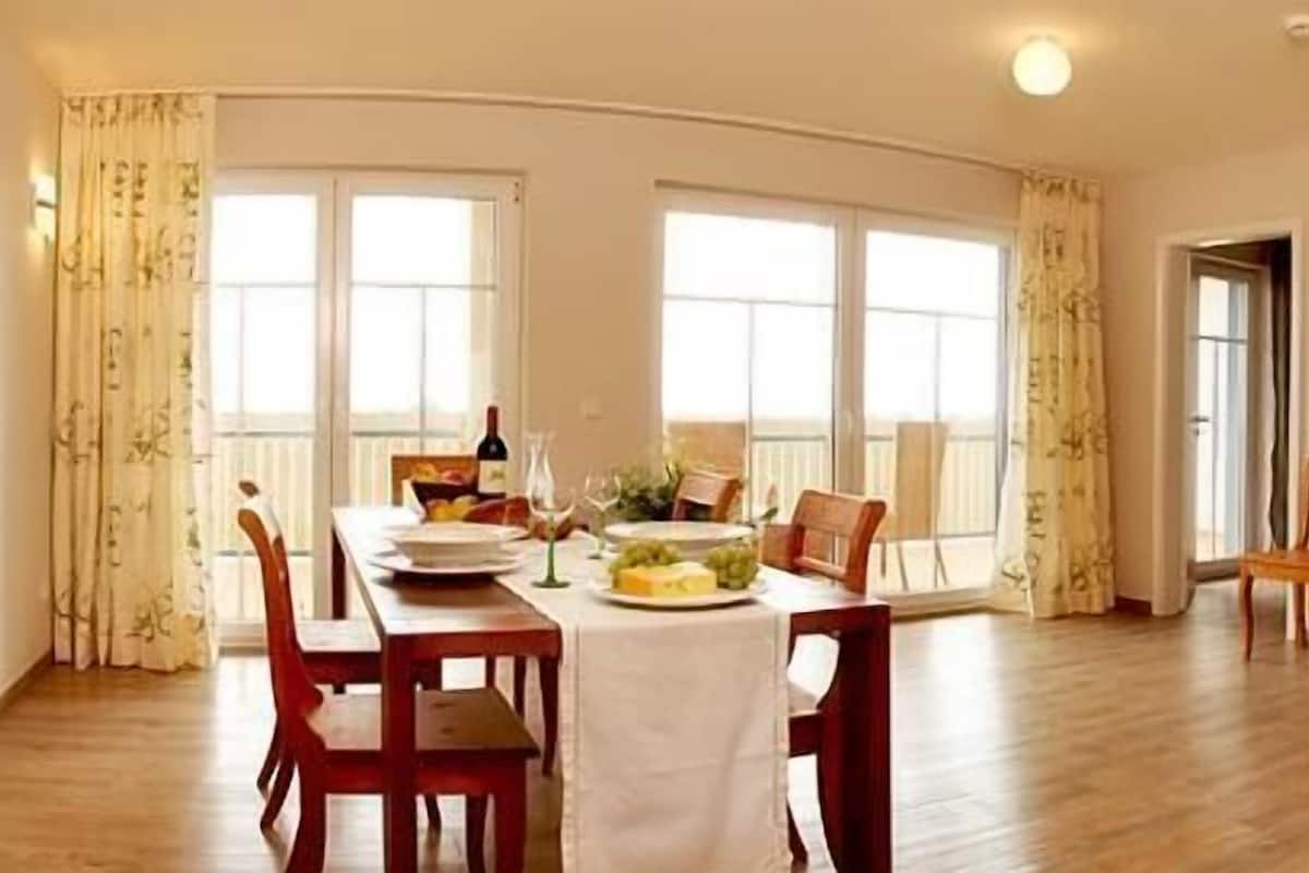 Un coin repas avec une table dressée pour quatre personnes, un téléviseur et un tableau accroché au mur.