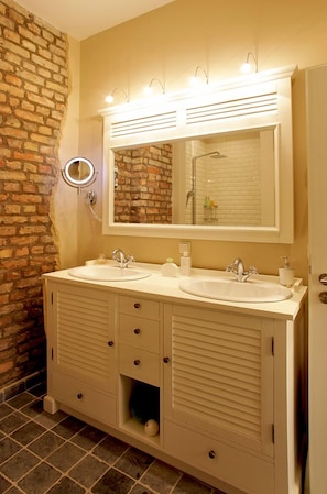 Een badkamer met twee wastafels, een grote spiegel en een ronde spiegel boven het aanrecht.