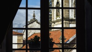 Ein Fenster mit Blick auf ein Gebäude mit einem Ziegeldach und einem Kreuz.