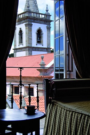 A room with a view of a building with a red roof and a bell tower. - Casa do Correio Mor (Ponte da Barca)