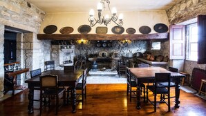 Ein rustikaler Essbereich mit Holztischen und -stühlen, einem Steinkamin und einer Kandelaber.