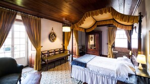 Ein traditionelles Himmelbett mit Baldachin, eine hölzerne Bank und ein gemusterter Boden.