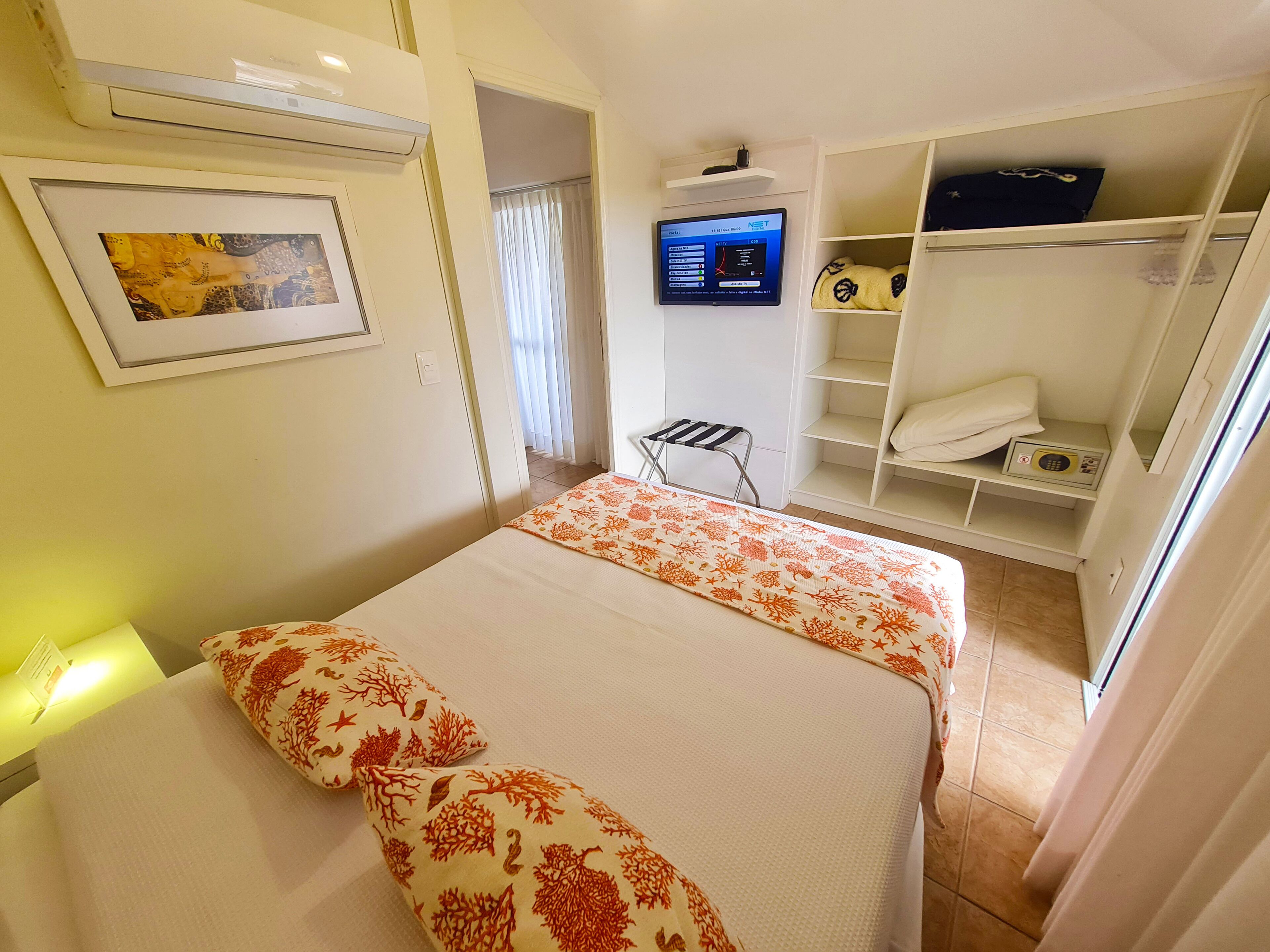 A hotel room with two beds, a TV, a wardrobe, and a small table.