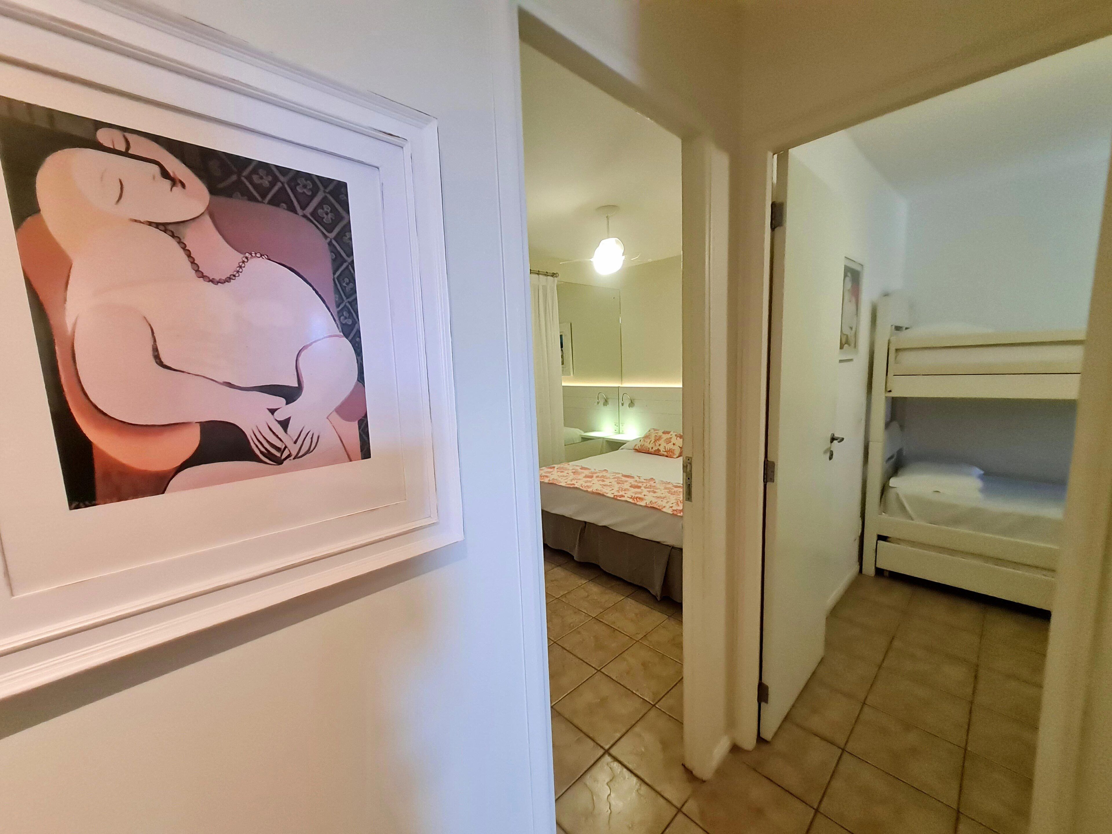 A hotel room with a bed, a bathroom with a mirror, and a framed artwork on the wall.