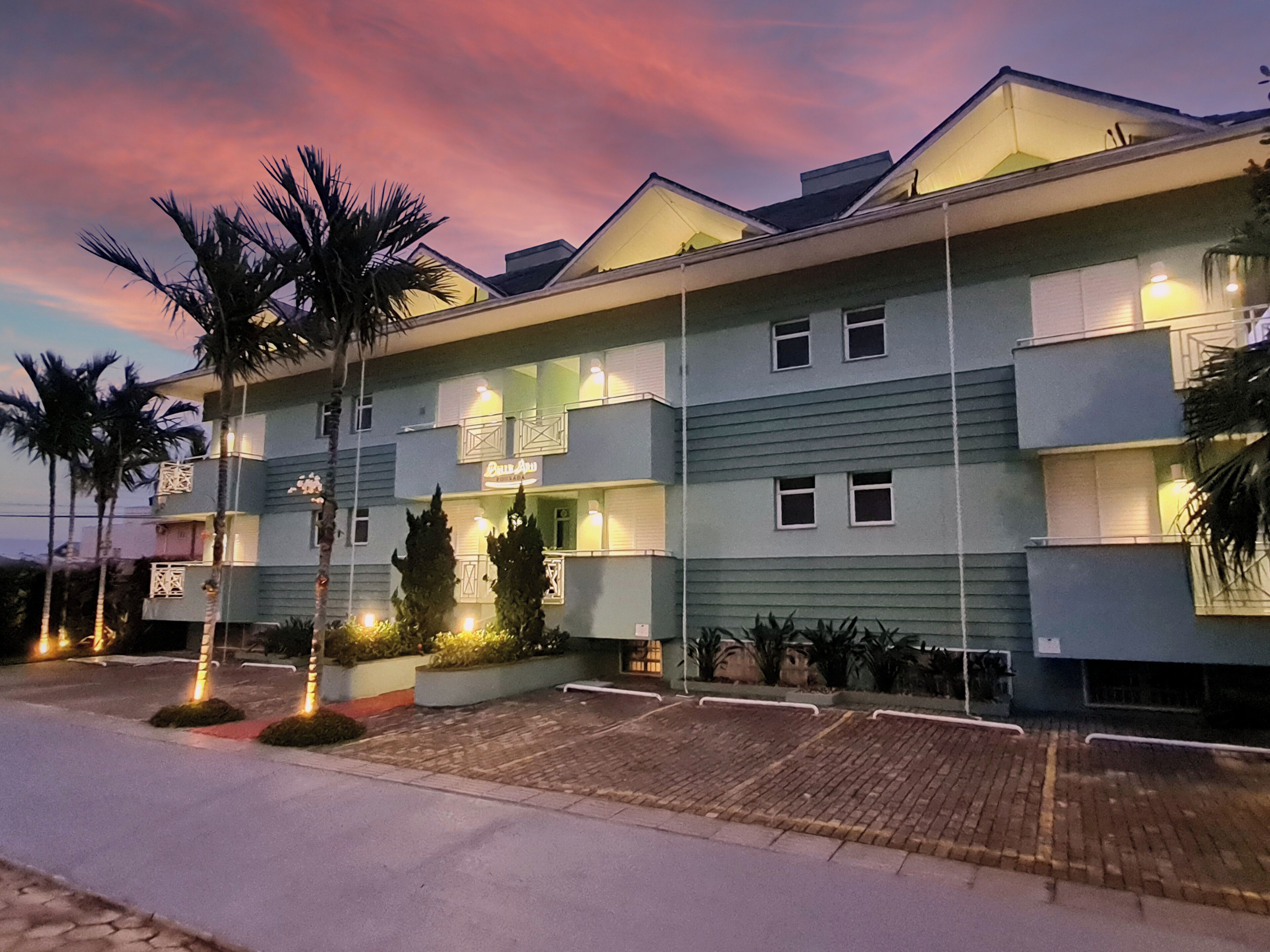 A multi-story hotel with a flat roof, balconies, and a well-lit entrance.