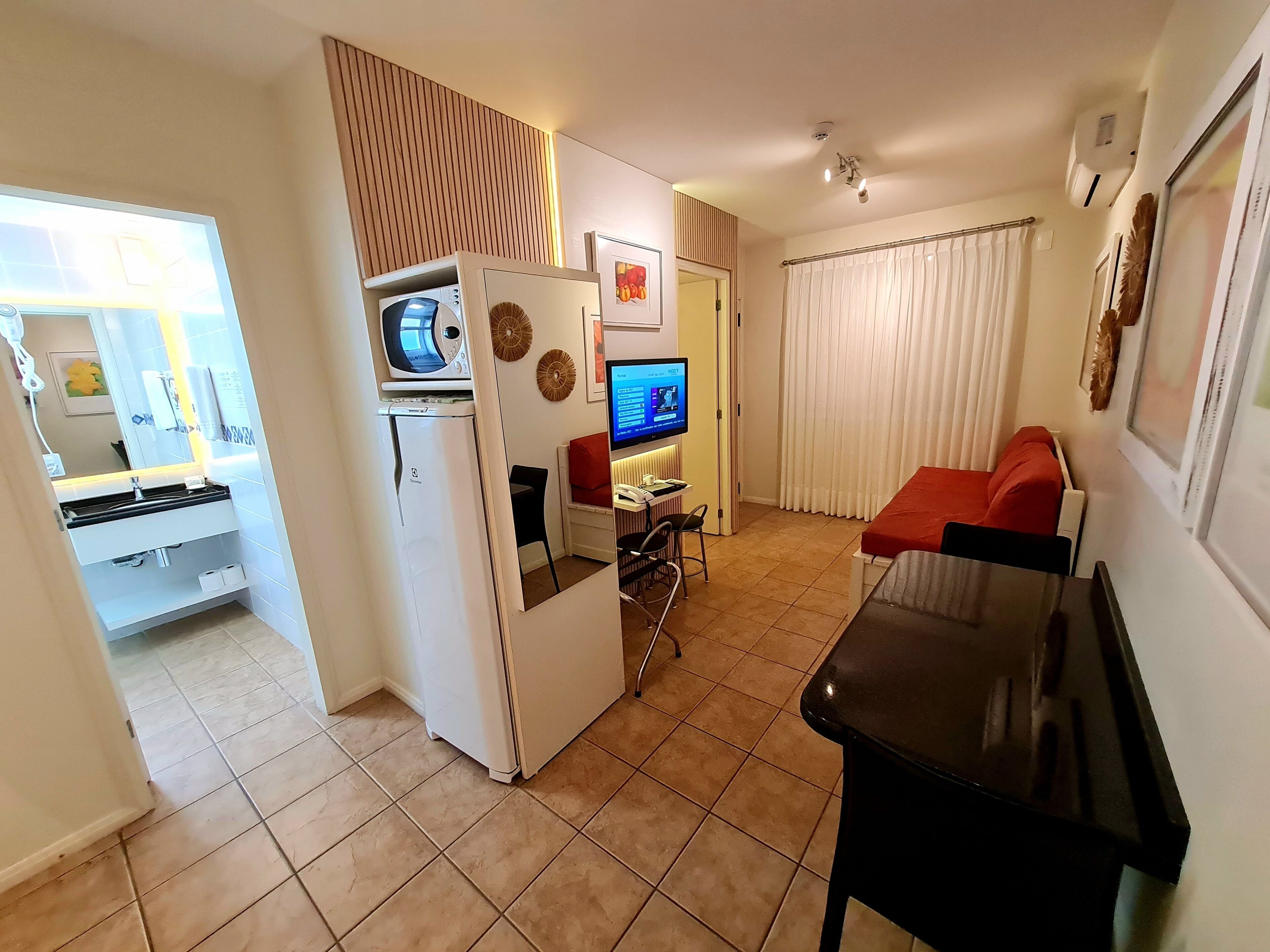 A compact living space with a kitchenette, a dining area, and a TV.