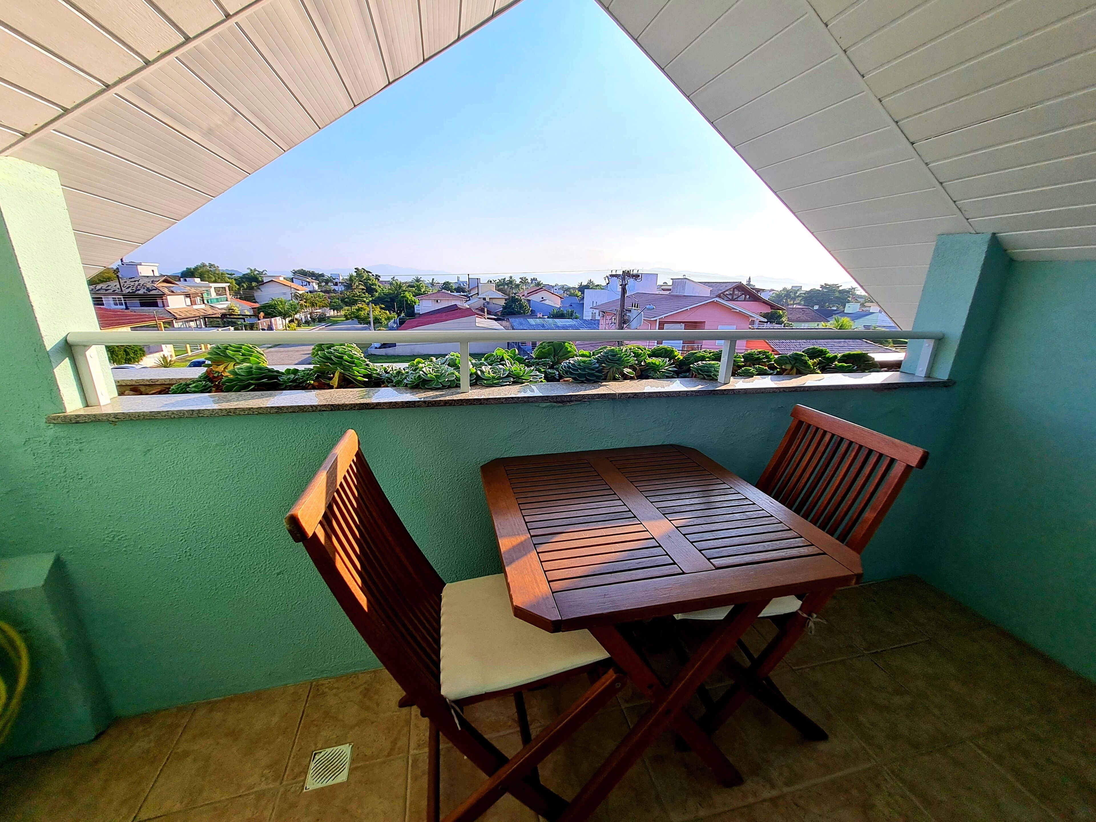 Ein Balkon mit Blick auf eine Wohngegend, einem Tisch und zwei Stühlen.